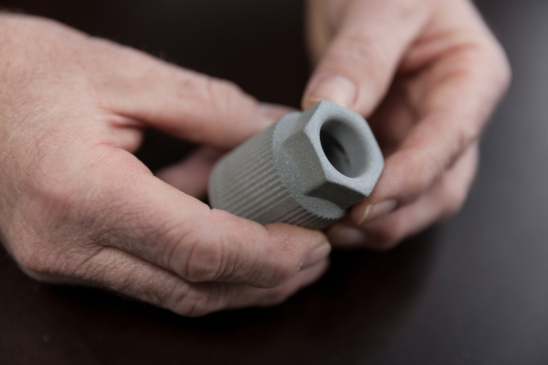 Zwei Hände halten ein Metallbauteil